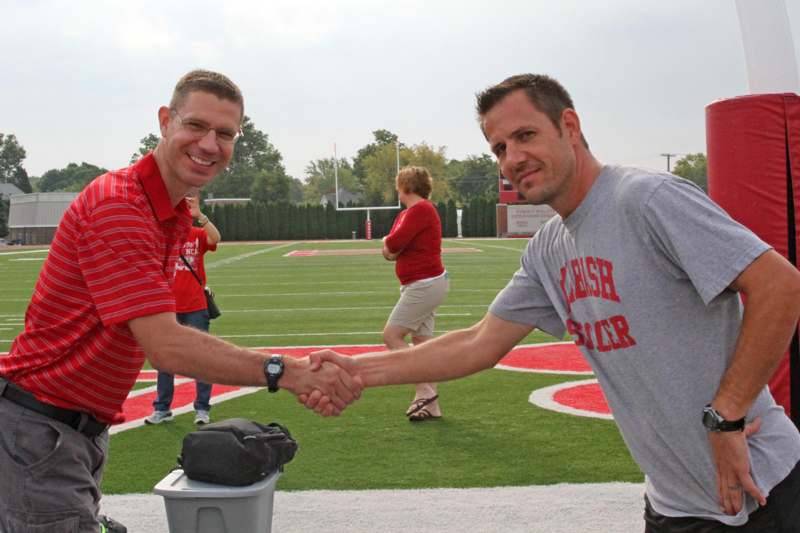men shaking hands on a football field