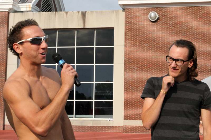 a man holding a microphone next to a man in glasses