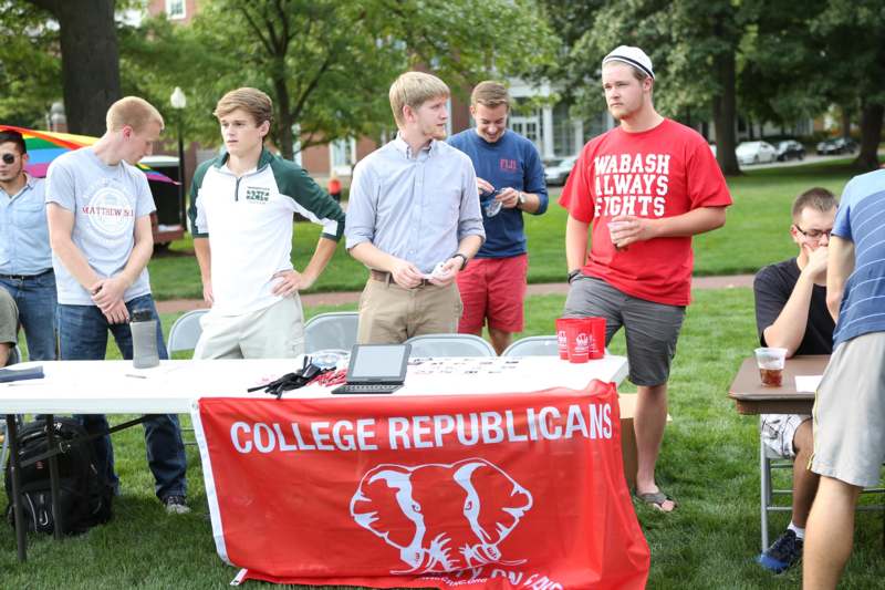 a group of men standing around a table with a red banner