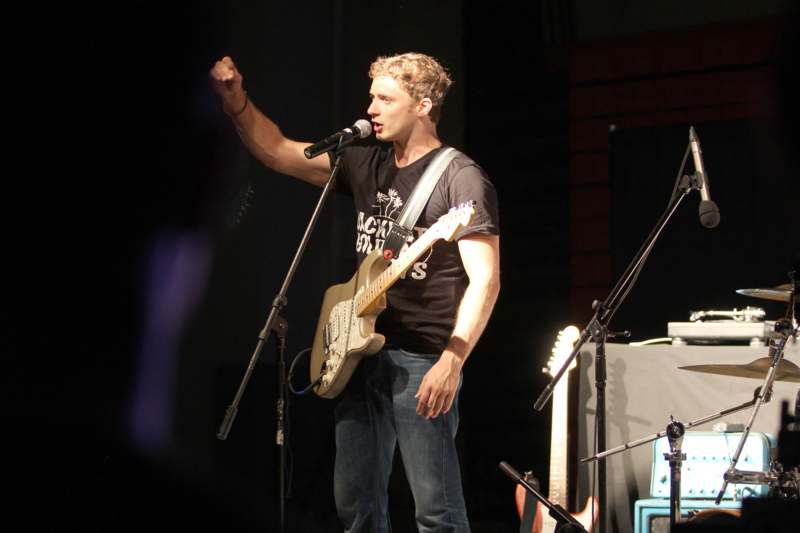 a man holding a guitar and standing on a stage