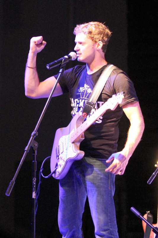 a man holding a guitar and singing into a microphone