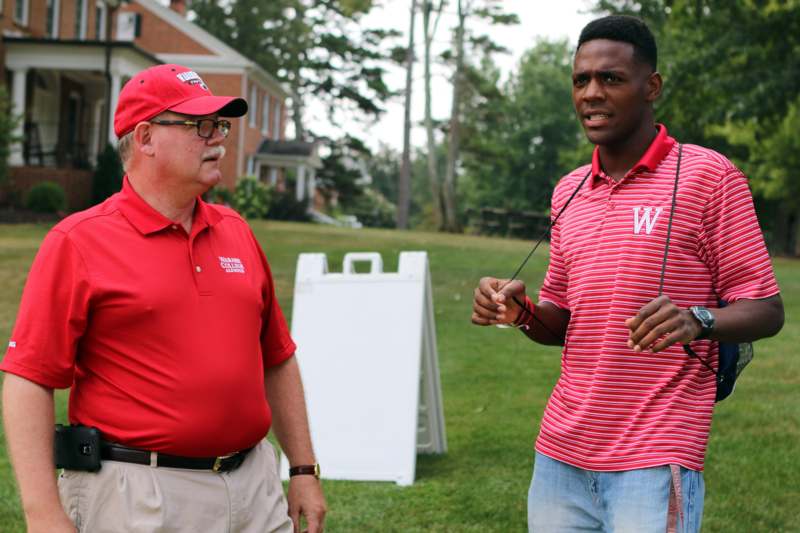 a man in red shirt talking to another man in a field