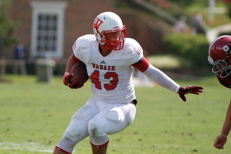 a football player in a white uniform with a red helmet holding a football