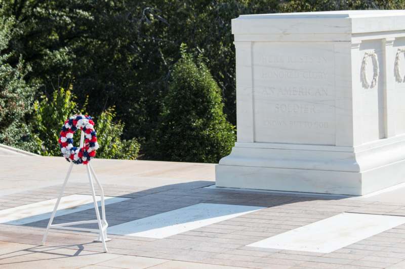 a wreath on a stand next to a white monument