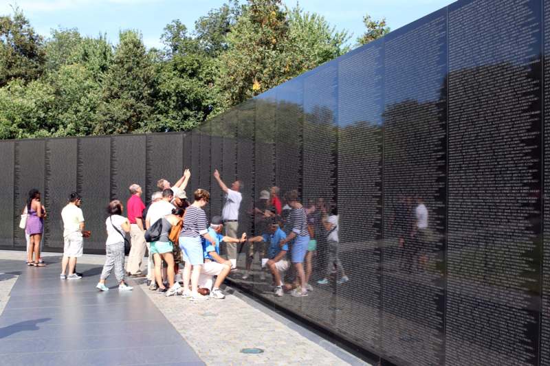 a group of people standing in front of a wall with Vietnam Veterans Memorial in the background