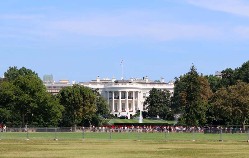a large white house with a large lawn and a fountain with White House in the background