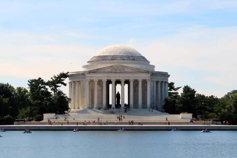 a white building with columns and a dome with Jefferson Memorial in the background