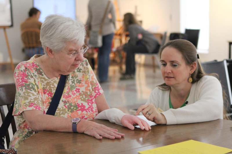 a woman sitting at a table with a woman looking at her hand