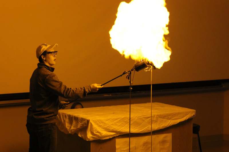 a man holding a stick with a large flame