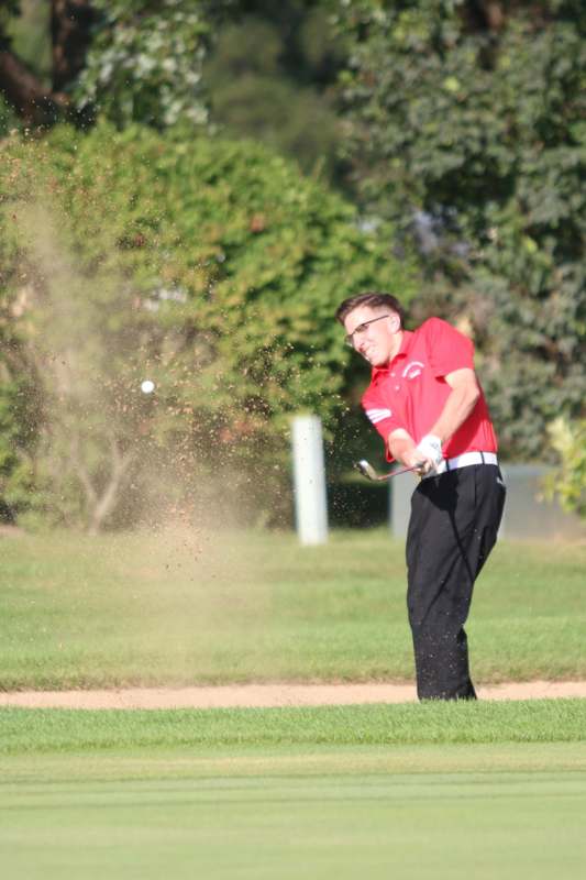 a man in a red shirt and black pants playing golf