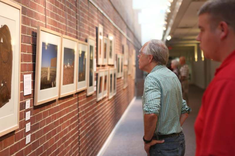 a man looking at a wall with pictures on it