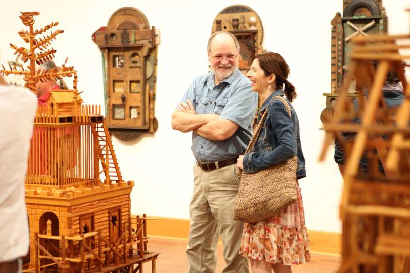 a man and woman standing in a room with wooden objects
