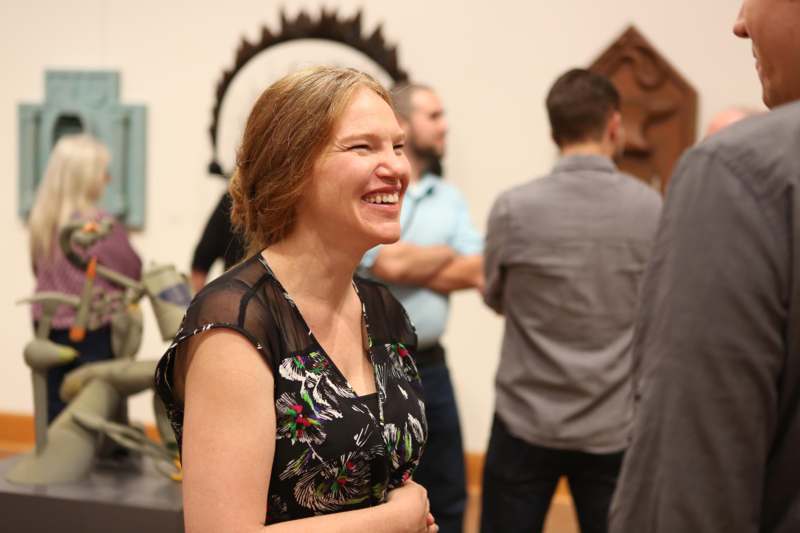 a woman smiling in a room with people in the background