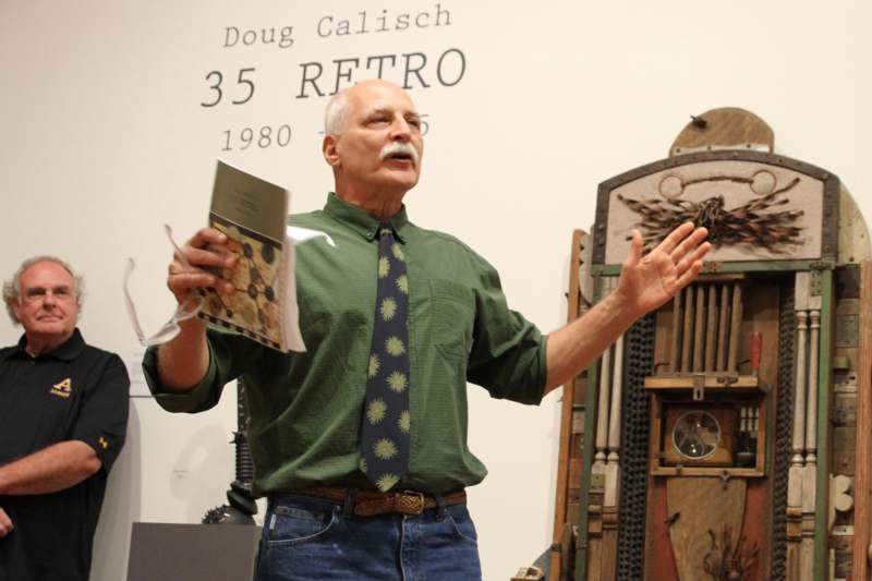 a man holding a book and standing in front of a wall