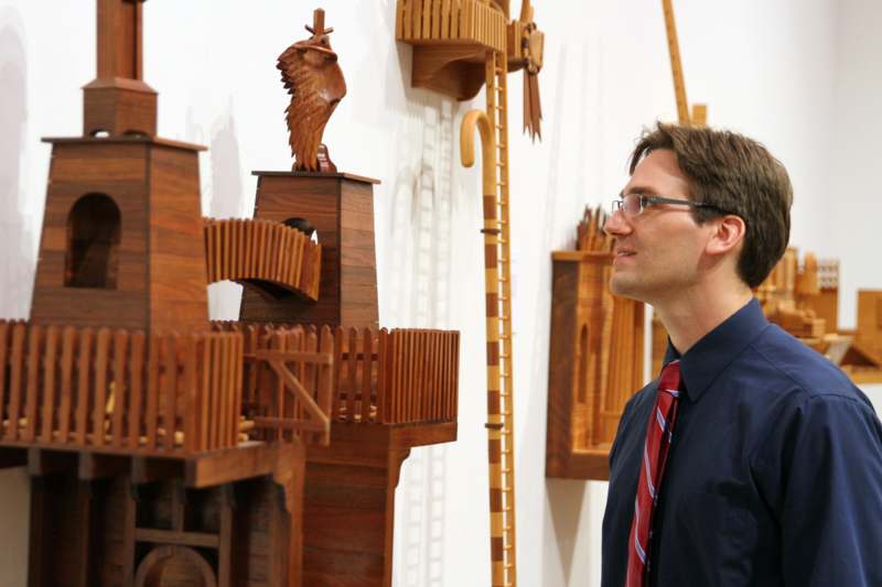 a man looking at a wooden sculpture