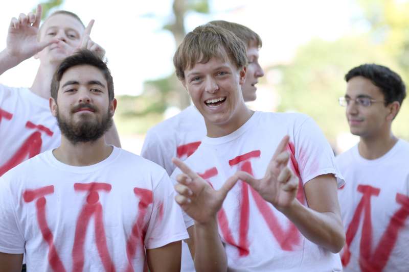a group of men wearing white t-shirts with red letters on them