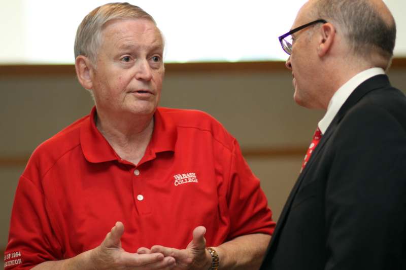 a man in a red shirt talking to another man