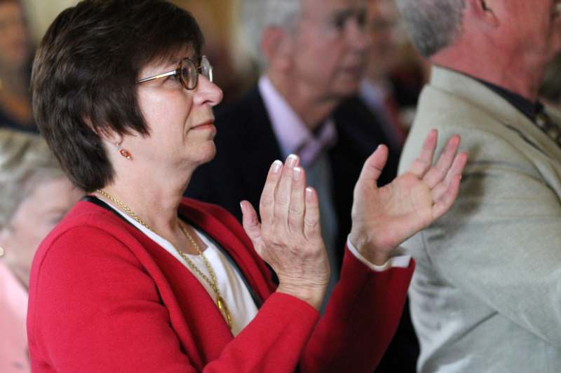 a woman in red jacket and glasses clapping hands