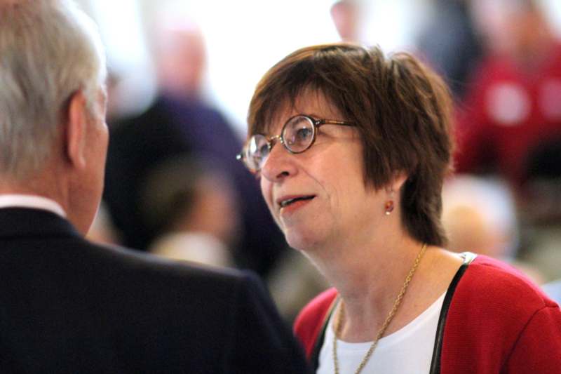 a woman wearing glasses and a red vest talking to a man