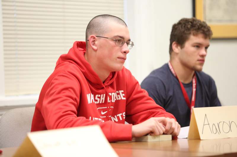 a man in a red sweatshirt sitting at a table