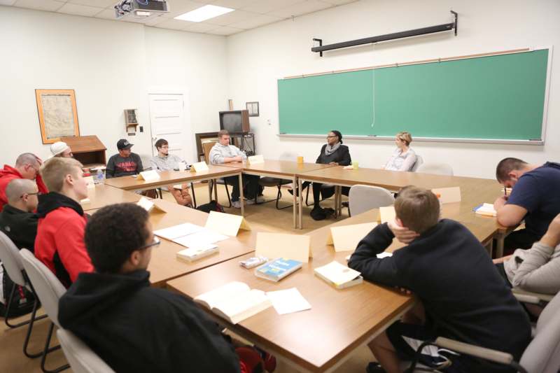 a group of people sitting at tables in a classroom