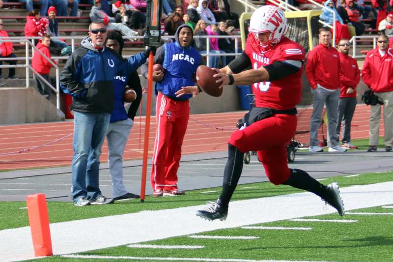 a football player in a red uniform running with a football in the air