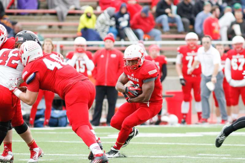 a football player in red uniform running with a ball