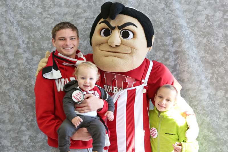 a man holding a child and a mascot posing for a picture