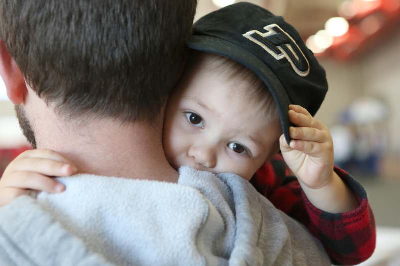 a baby in a hat on a man's shoulder