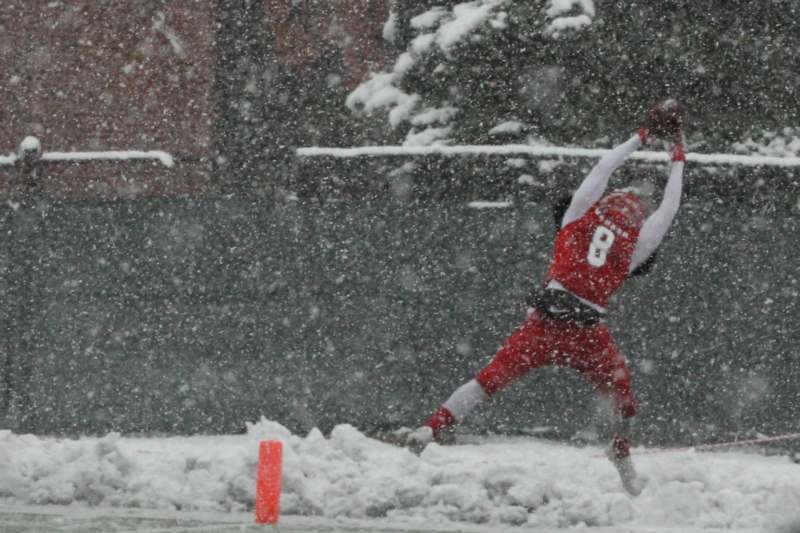 a football player catching a ball in the snow