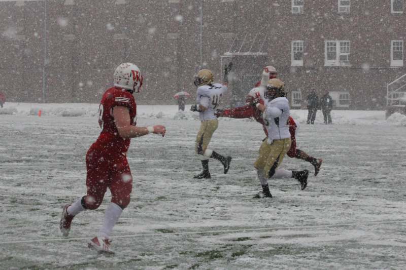 a group of football players running on a snowy field