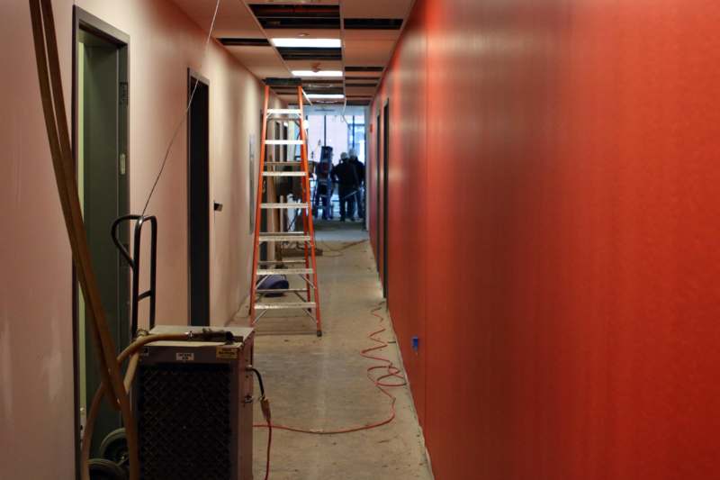 a long hallway with ladders and a red wall