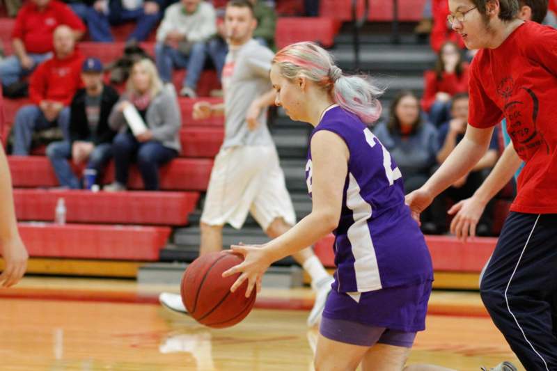 a woman in a purple uniform dribbling a basketball
