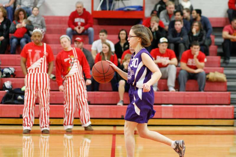 a woman in a purple uniform dribbling a basketball