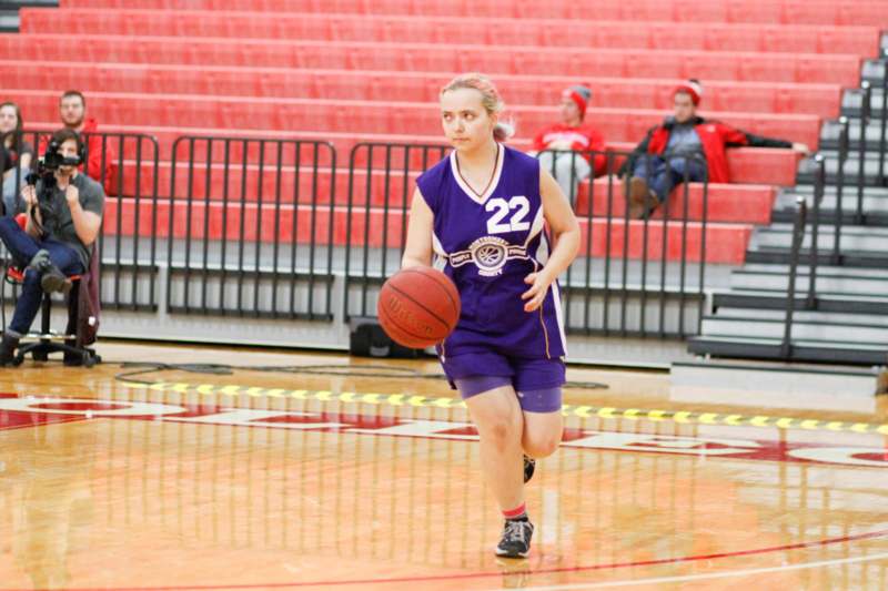a woman in a purple uniform running with a basketball