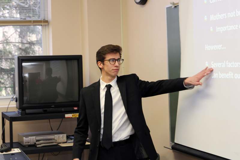 a man in a suit pointing at a whiteboard