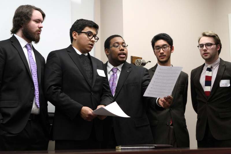 a group of men in suits holding a piece of paper