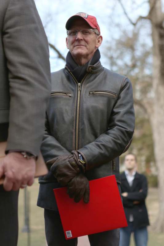 a man in a leather jacket holding a red folder