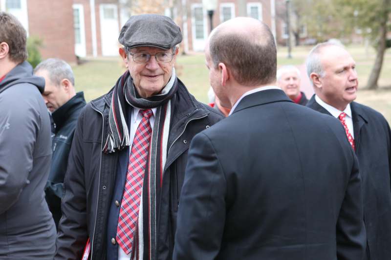 a man in a hat and scarf talking to another man