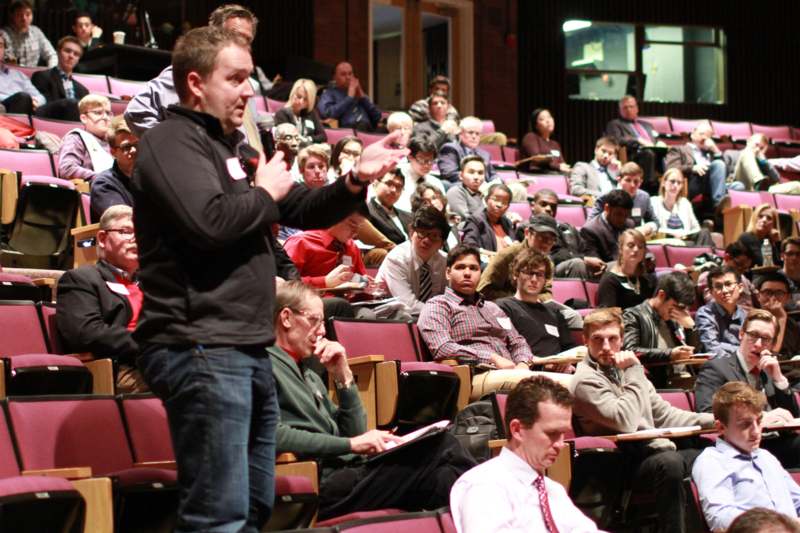 a man standing in front of a group of people in a lecture hall