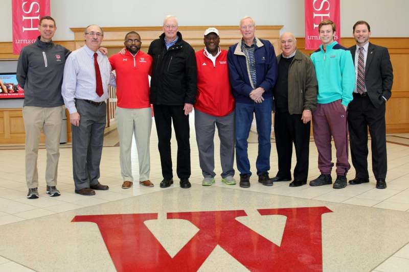 a group of men standing in a room with a red logo