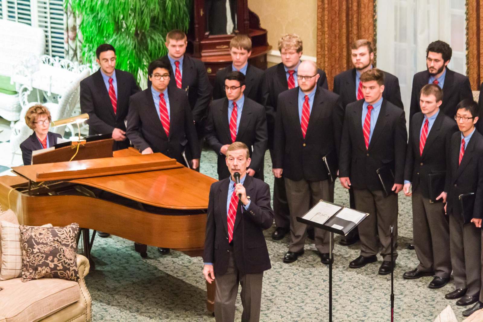 a group of men in suits and ties standing in front of a piano