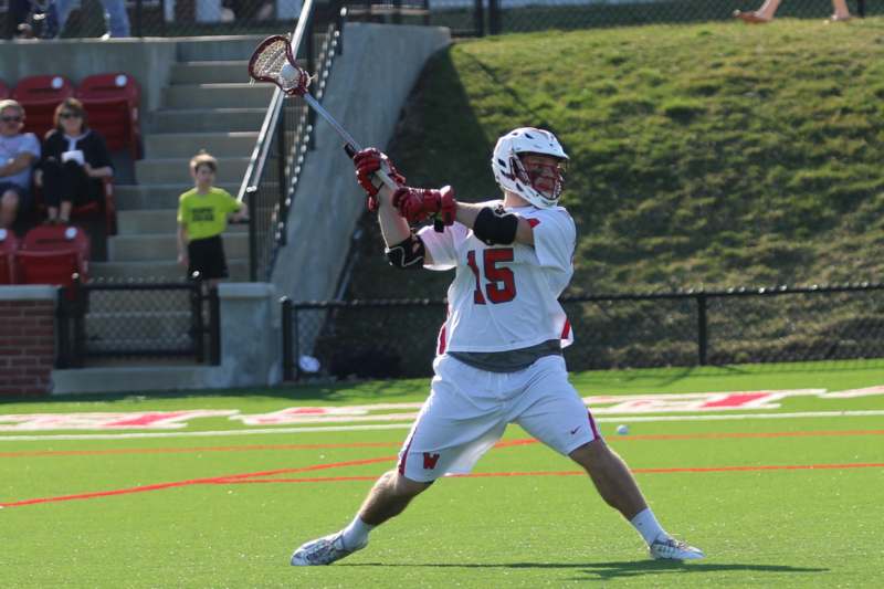 a man in a white shirt and helmet holding a lacrosse stick