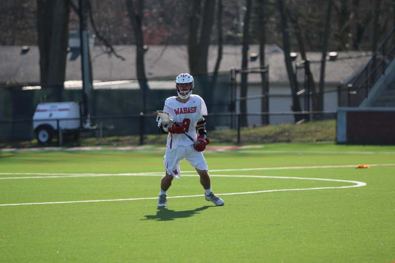 a man in a white and red uniform holding a lacrosse stick