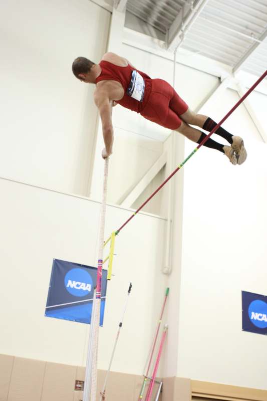 a man in red shorts jumping over a pole
