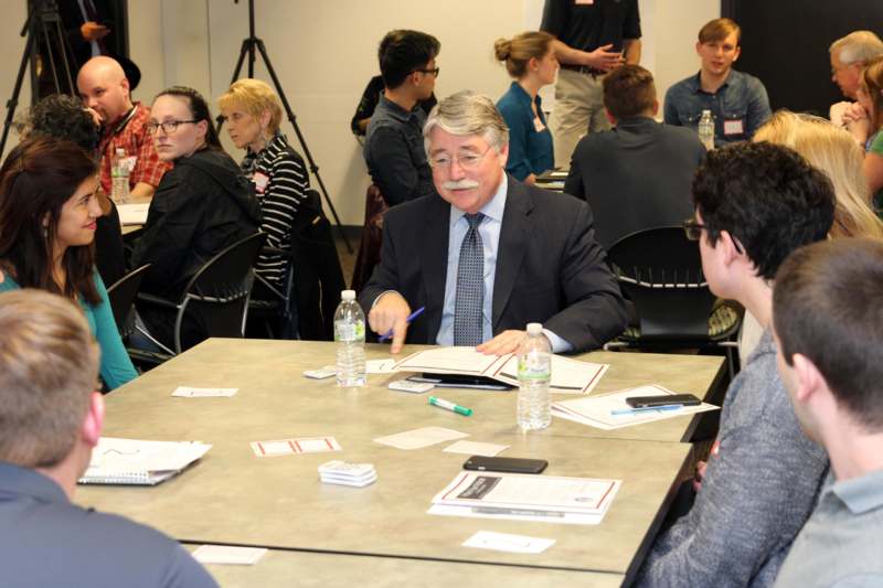 a man sitting at a table with other people around it