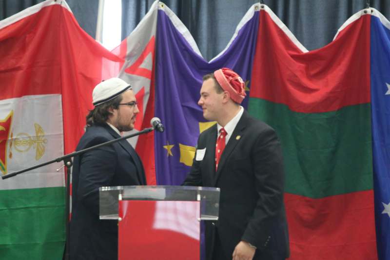 two men standing at a podium with a microphone in front of flags