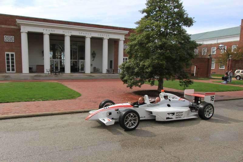 a white race car with red and white stripes on the front of a building