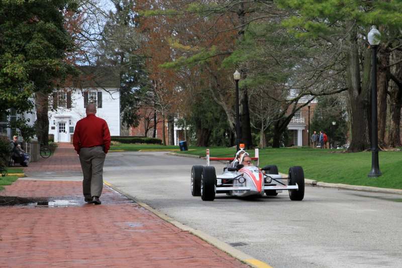 a man walking on a brick road with a race car on the side