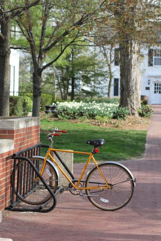 a yellow bicycle parked on a brick sidewalk